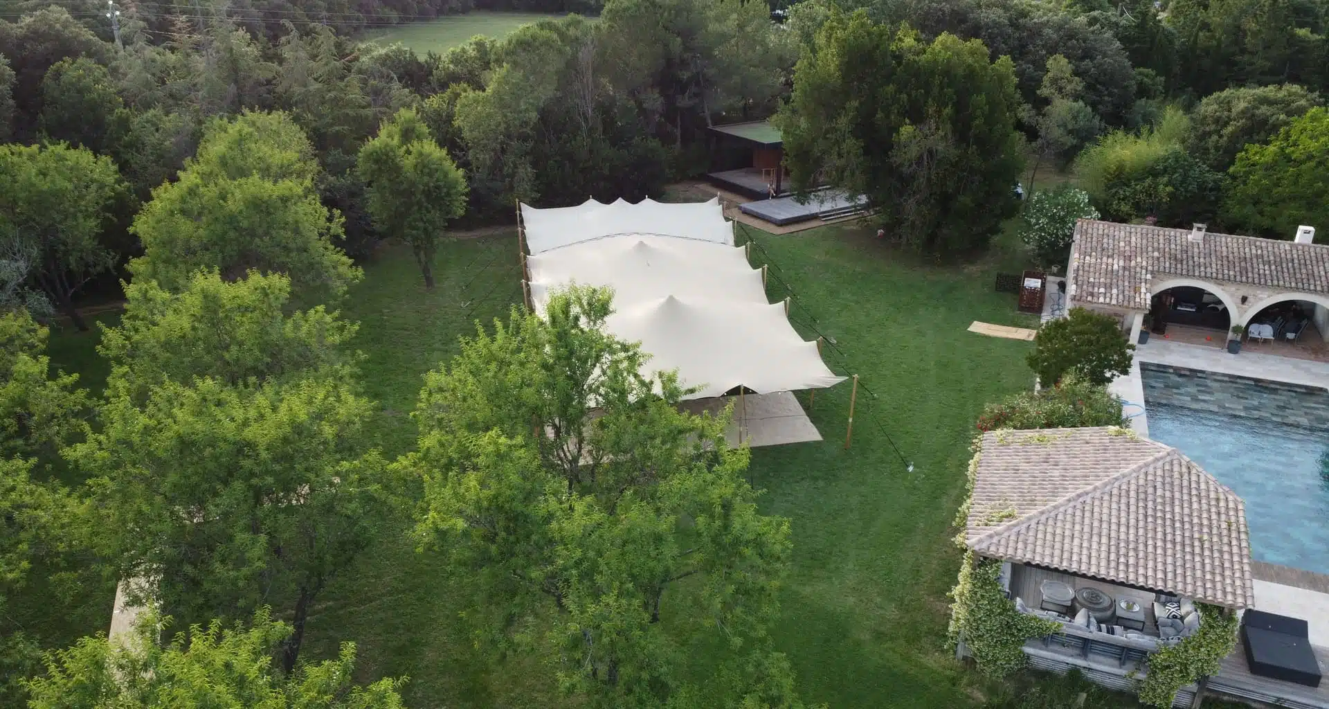 Installation d'une tente nomade pour un mariage à domicile au bord d'une piscine.
